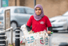A woman volunteer pushing a shopping trolley with groceries 