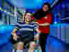 A Royal Voluntary Service hospital volunteer oushing a man with a bandaged leg in a wheelchair