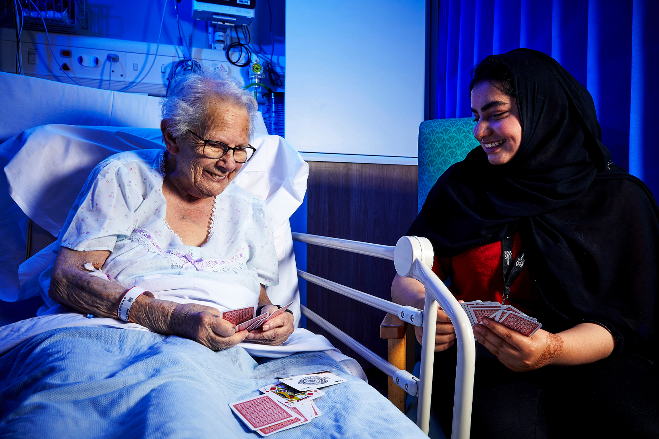 A young volunteer playing cards with a woman in hospital 