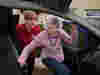 A Royal Voluntary Service driving volunteer helping an older lady in to a car 