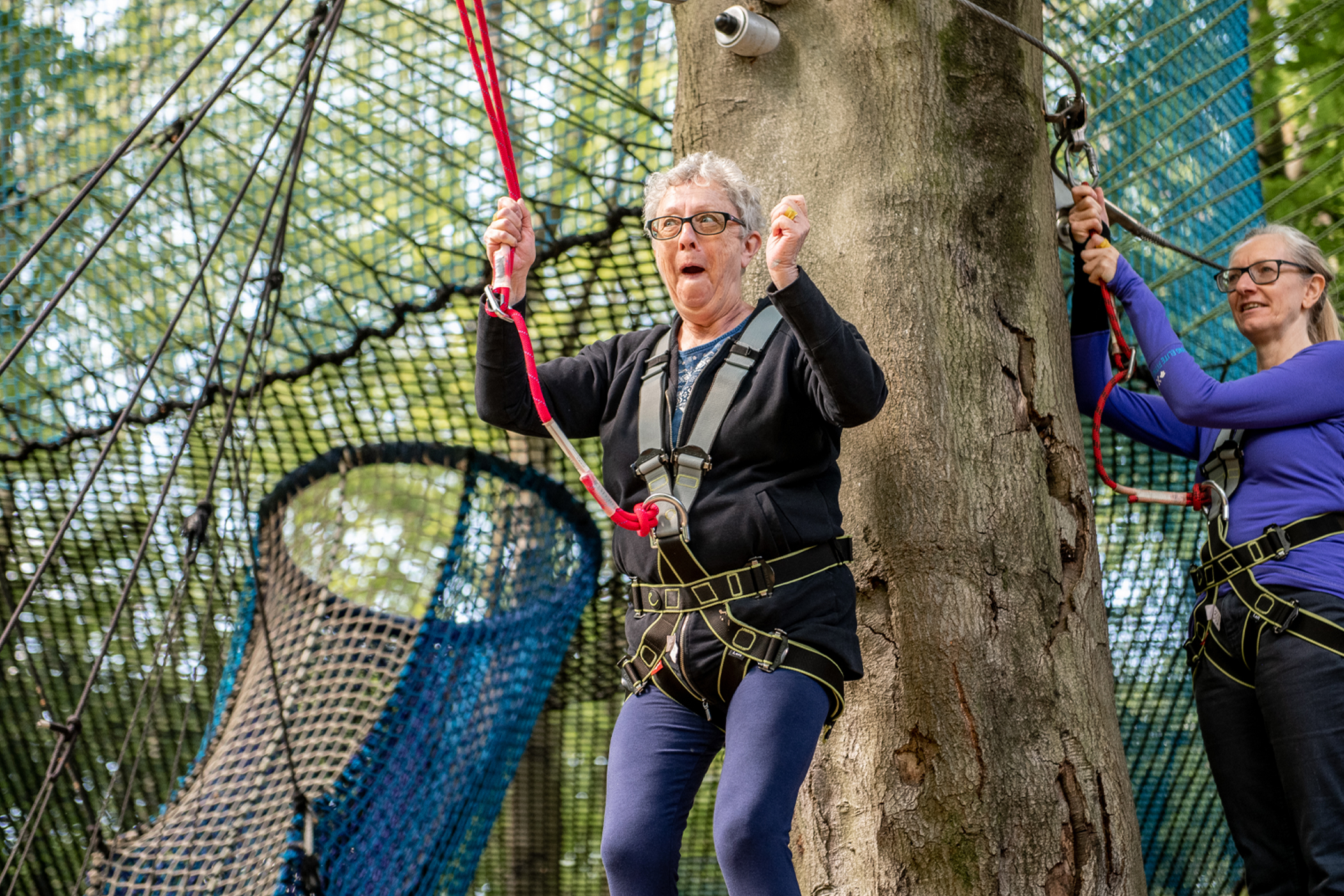 Older woman takes part in a treetops adventure course