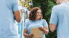 A female volunteer wearing a light blue T-shirt, smiling and looking happy with a clipboard