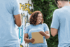 A female volunteer wearing a light blue T-shirt, smiling and looking happy with a clipboard