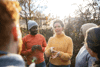 Young woman wearing the yellow jumper is giving directions to a group of volunteers outside in daylight