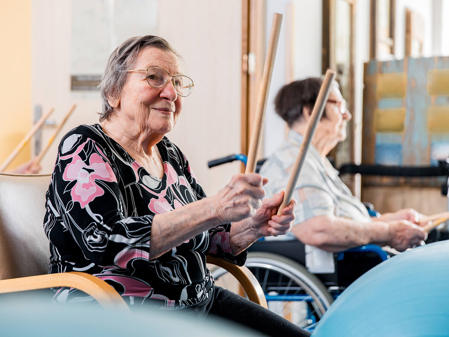 An older lady playing the drums in a group exercise session 
