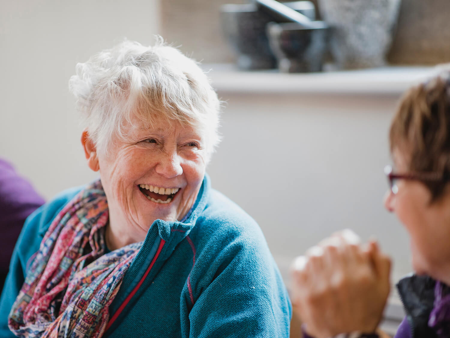 A happy older lady smiling at her friend in a Royal Voluntary service club 