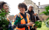 A woman smiling, whilst giving directions to others whilst gardening outside