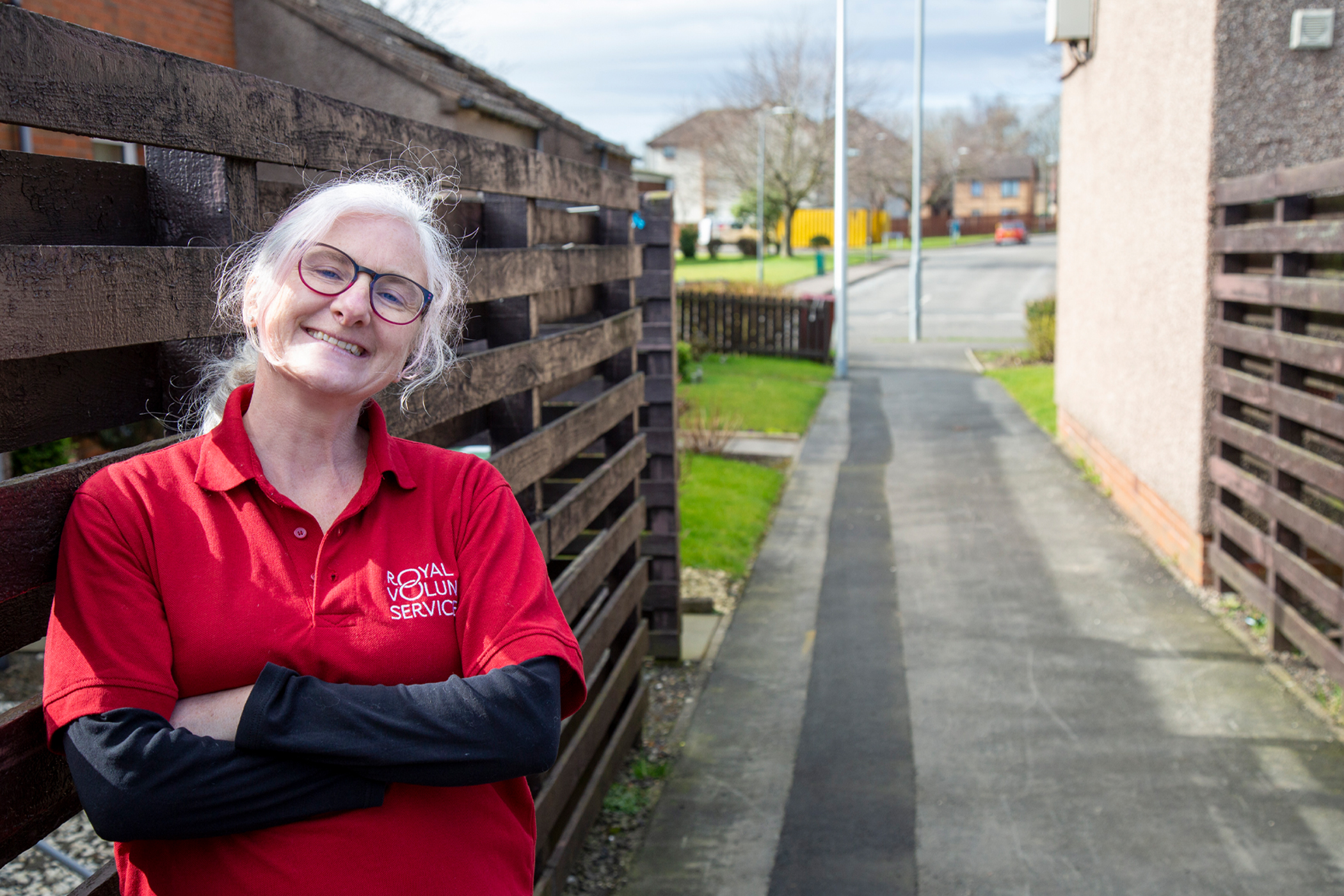 A Royal Voluntary Service volunteer leaning against a fence